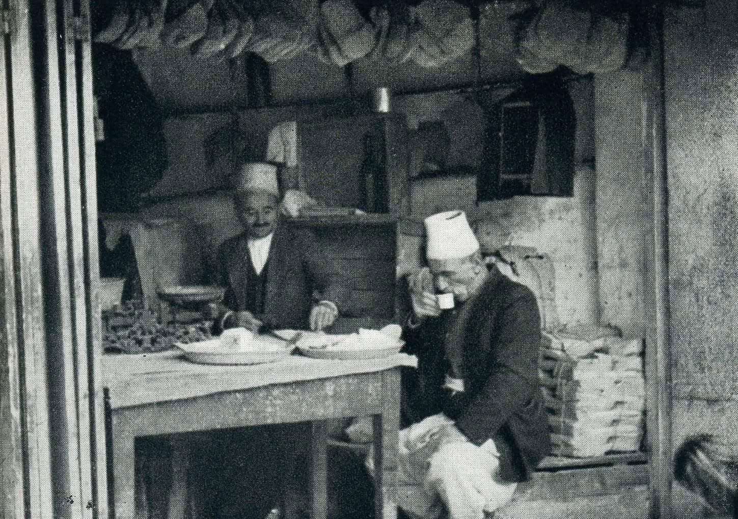 Pazari i Vjetër i Krujës — dyqan tradicional, burra me qeleshe, shekulli XX